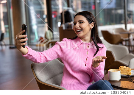 A girl in a pink shirt sitting in a cafe and feeling positive 108504084