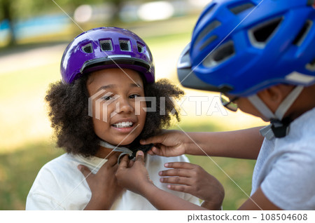 Siblings helping each other to put on a protective hemlet 108504608