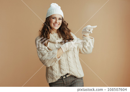 smiling elegant woman pointing at something on beige 108507604