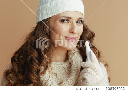 happy woman in beige sweater, mittens and hat on beige 108507622