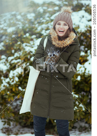 smiling woman outdoors in park in winter playing with snow 108508536