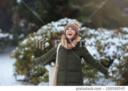 smiling modern woman outdoors in city park in winter 108508545