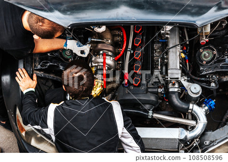 mechanics check the car engine before driving. under the hood. extreme sport. racing car engine problems. mechanics check the car engine before driving. under the hood. extreme sport. racing car engine problems. 108508596