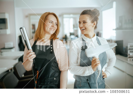 happy two women hairdressers in uniform in beauty studio happy two women hairdressers in uniform in beauty studio 108508631