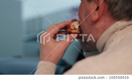 Man eats unhealthy fast food in modern car with view of city life from window. Adult man passenger eats fast food in car. Future health problems for man due to eating fast food in car Man eats unhealthy fast food in modern car with view of city life from window. Adult man passenger eats fast food in car. Future health problems for man due to eating fast food in car 108508916