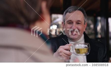 Man has conversation with woman drinking tea in transparent cups in park cafe. Walk of man and woman partners and tea drinking in cafe of park. Meeting of man and woman for tea in autumn cafe of park Man has conversation with woman drinking tea in transparent cups in park cafe. Walk of man and woman partners and tea drinking in cafe of park. Meeting of man and woman for tea in autumn cafe of park 108508918