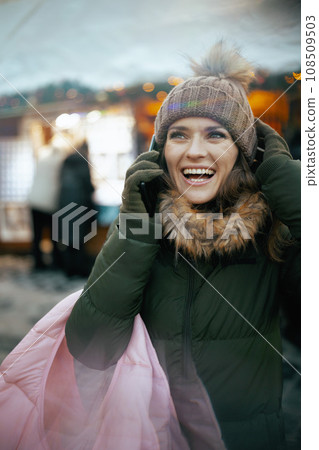 smiling female at winter fair in city talking on phone smiling female at winter fair in city talking on phone 108509503