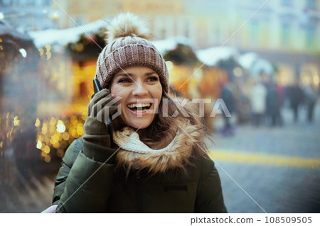 smiling woman at christmas fair in city talking on phone smiling woman at christmas fair in city talking on phone 108509505