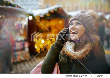 smiling female at winter fair in city talking on phone 108509506