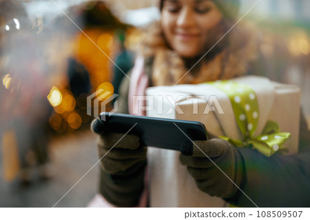 Closeup on woman at winter fair in city using smartphone Closeup on woman at winter fair in city using smartphone 108509507