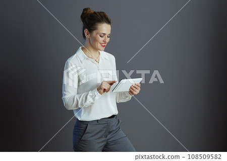 happy trendy business woman using applicationst PC against gray 108509582