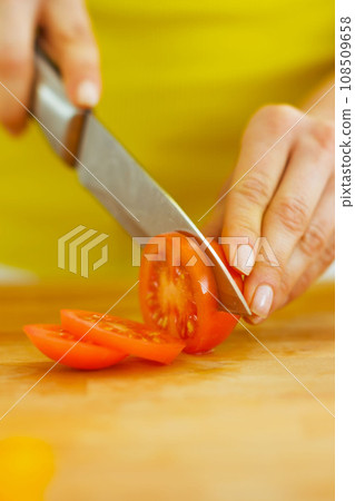 Closeup on woman cutting tomato Closeup on woman cutting tomato 108509658