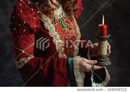Closeup on medieval queen in red dress with candle Closeup on medieval queen in red dress with candle 108509722