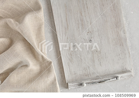 Fragment of a wooden white painted tray and a crumpled linen kitchen napkin on a light concrete table. Food menu mockup Fragment of a wooden white painted tray and a crumpled linen kitchen napkin on a light concrete table. Food menu mockup 108509969