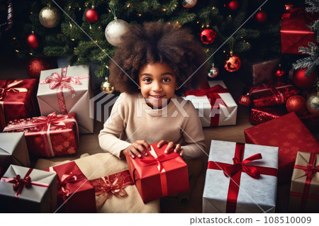 Happy little african american smiling girl with christmas gift boxes on floor 108510009
