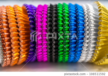 Close-up view. Multicolor foil lining cups for cupcakes on a marble countertop. 108511592