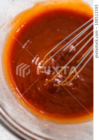 Mixing ingredients with a hand whisk to make a sweet glaze for meatloaf. 108511593