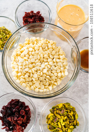 Measured ingredients in glass mixing bowls to prepare cranberry pistachio fudge. 108511618