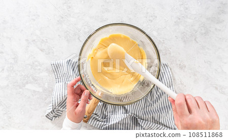 Flat lay. Melting white chocolate chips and other ingredients in a glass mixing bowl over boiling water to prepare cranberry pistachio fudge. 108511868