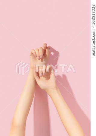 Beautiful groomed womans hands with pink matte nail design on a pink background. Manicure, pedicure beauty salon 108512328