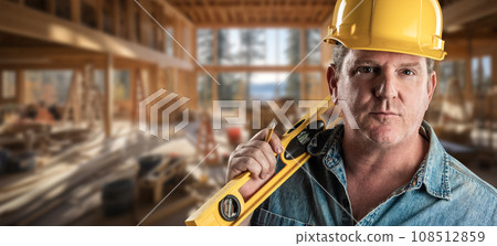 Hard Working Male Contractor at a Construction Site Wearing a Hard Hat and Work Gloves Holding His Level. Hard Working Male Contractor at a Construction Site Wearing a Hard Hat and Work Gloves Holding His Level. 108512859