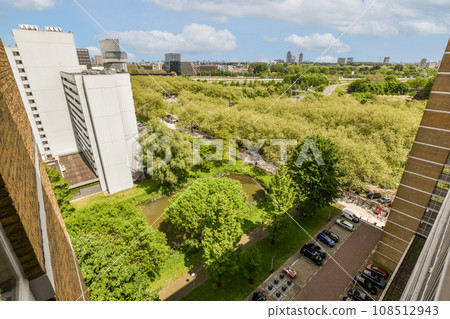 an urban area with buildings and trees in the fore, taken from a high angle on a clear blue sky day 108512943