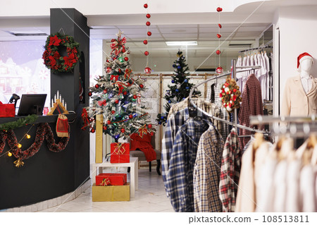 Empty festive clothing store during christmas season, beautifully decorated xmas tree and ornaments in fashion center boutique. Retail shop inside mall waiting for clients during holiday season. Empty festive clothing store during christmas season, beautifully decorated xmas tree and ornaments in fashion center boutique. Retail shop inside mall waiting for clients during holiday season. 108513811