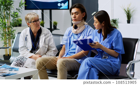 Elderly medic explaining medical expertise with assistant in hospital waiting room, discussing health care treatment with injured patient. Asian man wearing cervical neck collar during consultation 108513905