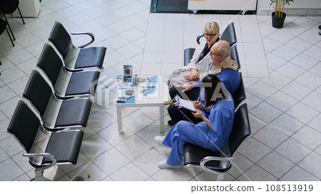 General practitioner doctor and nurse helping old man to take off cervical neck collar during checkup visit appointment in hospital waiting room. Elderly patient receiving medicine support General practitioner doctor and nurse helping old man to take off cervical neck collar during checkup visit appointment in hospital waiting room. Elderly patient receiving medicine support 108513919