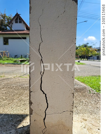 Cracks in damaged building pillars. Cracked concrete pillar of an old house. Deep and clear fractures, on the front surface of an old cement pillar. 108515668