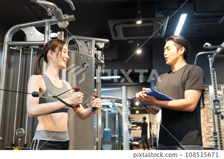 A woman receiving guidance from a trainer at a training gym 108515671