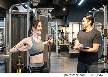 A woman receiving guidance from a trainer at a training gym 108515675