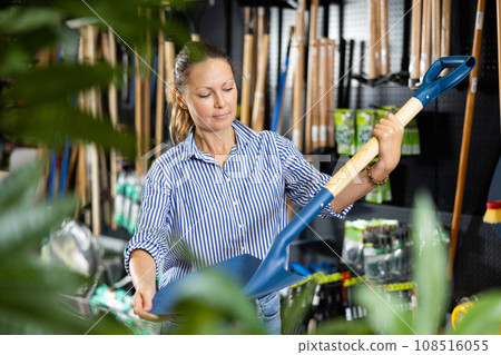 Woman choosing shovel in store 108516055