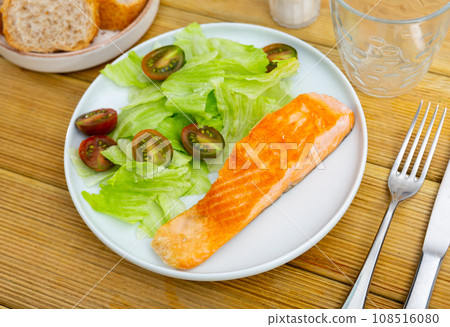 Mediterranean cuisine.slice of fried salmon with green salad and cherry tomatoes, white bread Mediterranean cuisine.slice of fried salmon with green salad and cherry tomatoes, white bread 108516080