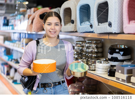 Young happy woman choosing bowl for pets in pet shop 108516118