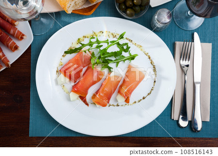 Tasty dish rolls of prosciutto di parma with melon served with arugula at plate 108516143