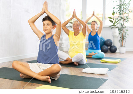 Preteen boy practicing lotus pose of yoga in light fitness room Preteen boy practicing lotus pose of yoga in light fitness room 108516213