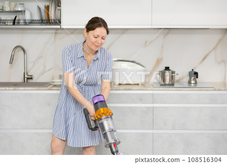 Housewife does cleaning in room - vacuums and dusts Housewife does cleaning in room - vacuums and dusts 108516304