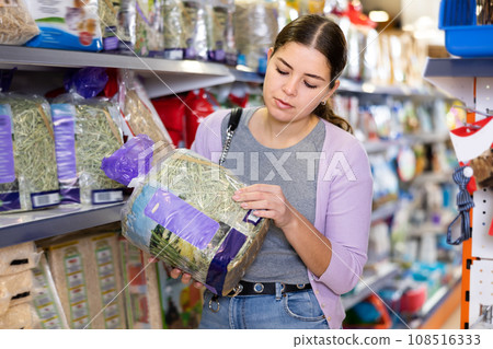 Young woman choosing dry straw for bedding for rabbit cage Young woman choosing dry straw for bedding for rabbit cage 108516333