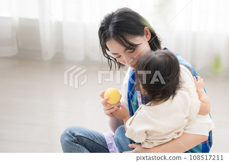 A young female nursery worker holding a small child and playing with toys A young female nursery worker holding a small child and playing with toys 108517211