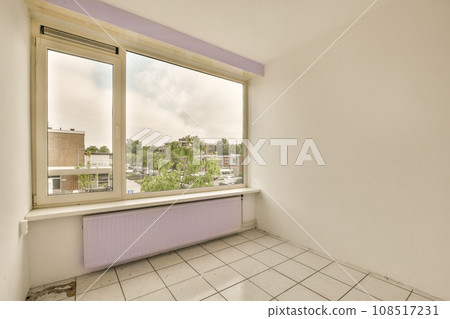 an empty room with white tile flooring and purple painted window sims on the right side of the room an empty room with white tile flooring and purple painted window sims on the right side of the room 108517231
