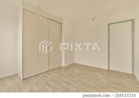 an empty room with white walls and wood flooring the door is open on the right side of the room 108517233