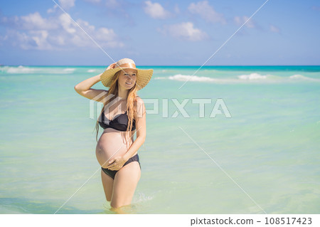 Radiant and expecting, a pregnant woman stands on a pristine snow-white tropical beach, celebrating the miracle of life against a backdrop of natural beauty Radiant and expecting, a pregnant woman stands on a pristine snow-white tropical beach, celebrating the miracle of life against a backdrop of natural beauty 108517423