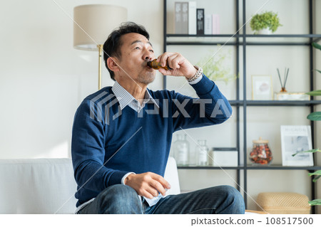 A middle-aged man drinking an energy drink in the living room 108517500