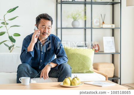 一位老人在客廳使用智慧型手機。 108518085