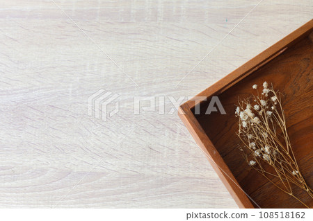 Tray with a dried flowers on a wooden table 108518162