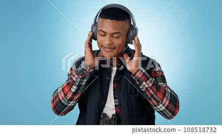 Happy, man and headphones in studio for music, podcast and relax with audio subscription on blue background. Smile, freedom and young model listening to sound, streaming multimedia and hearing radio 108518732