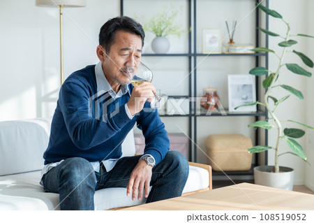 Middle-aged man drinking white wine in the living room 108519052