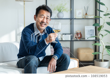 中年男子在客廳喝白葡萄酒 中年男子在客廳喝白葡萄酒 108519053