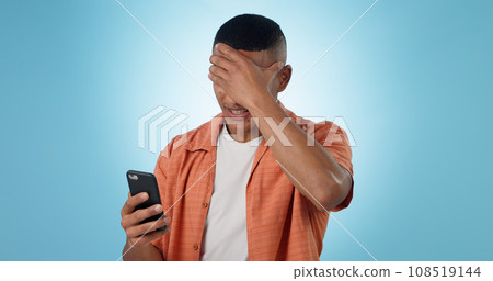 Man, phone and shock for bad news in studio for negative text message, disappointment or loss. Male person, mobile and connection or social media for unhappy discussion, blue background as mockup 108519144